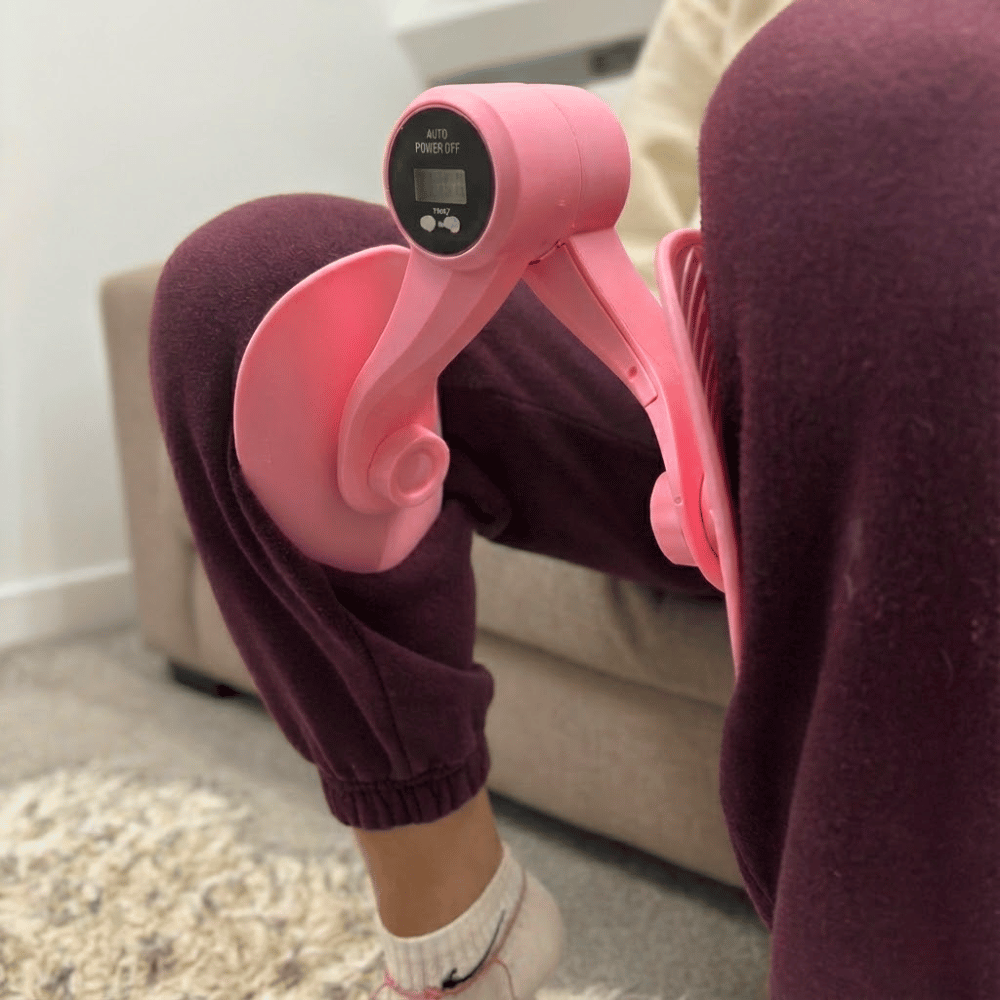 Person using a pink abdominal exercise machine on a carpeted floor.